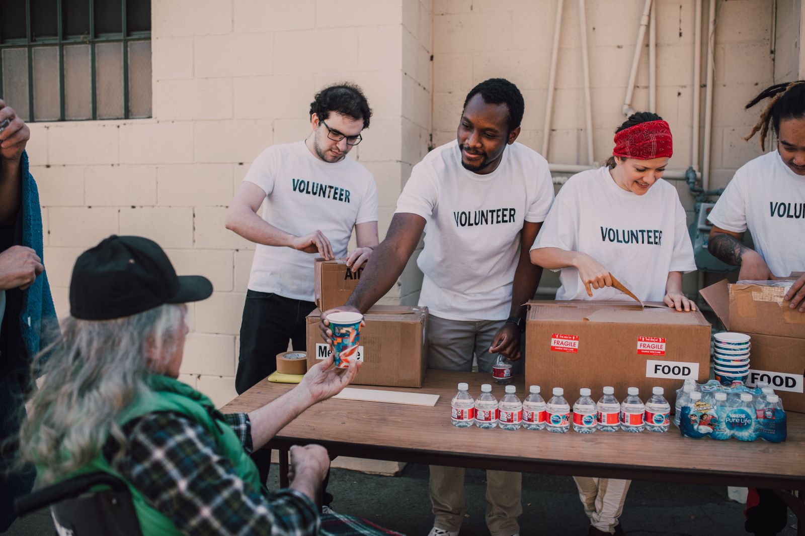 Volunteers of different races and ages working together at an outdoor food donation table